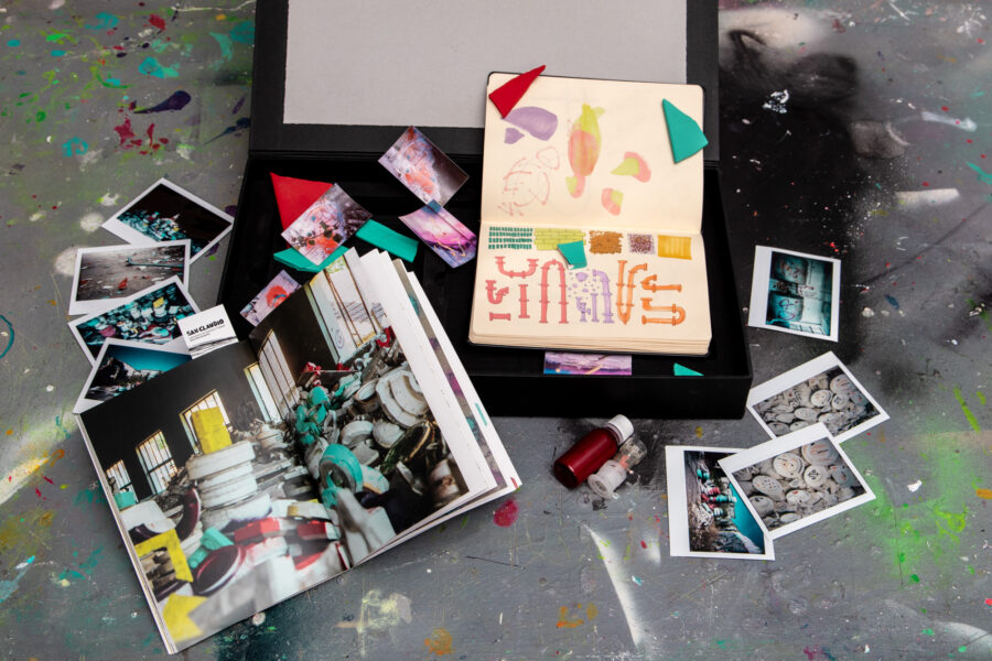 El fanzine San Claudio.Lab en su caja, con fotos y pegatinas, sobre un suelo manchado de pintura