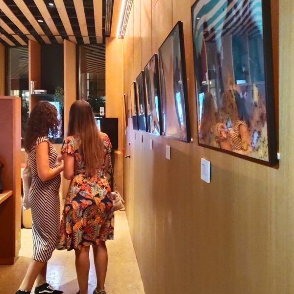 Dos visitantes mirando la serie completa en el vernissage del Hotel Ocean Drive Madrid