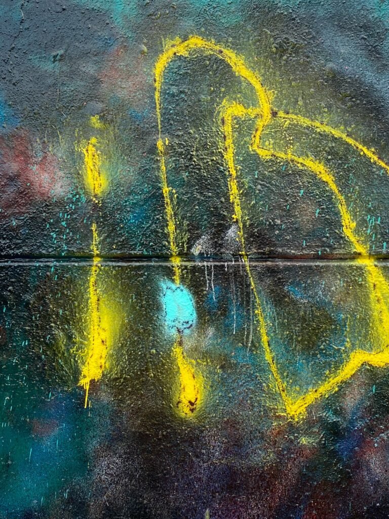 Detalle de trazos amarillos verticales y curvos sobre el fondo oscuro, con una mancha turquesa.