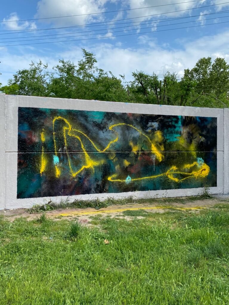 El mural terminado visto en escorzo, en vertical, con árboles y cielo azul detrás.