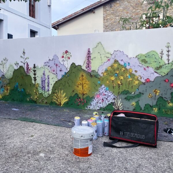 El mural casi terminado, con sprays, un bote de pintura y la bolsa de material en el suelo