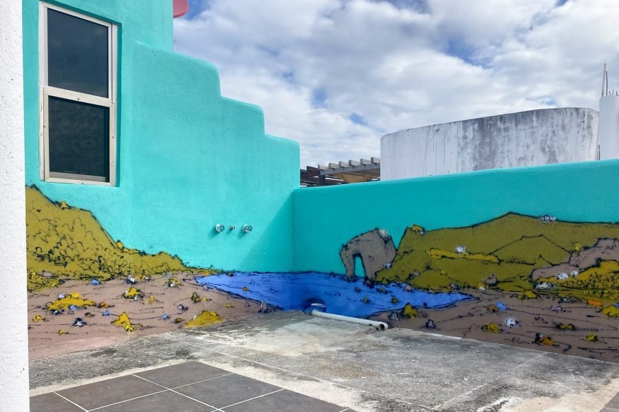 La esquina del mural: el mar y las colinas pasan de una pared a la otra, con el arco de roca junto a la esquina.