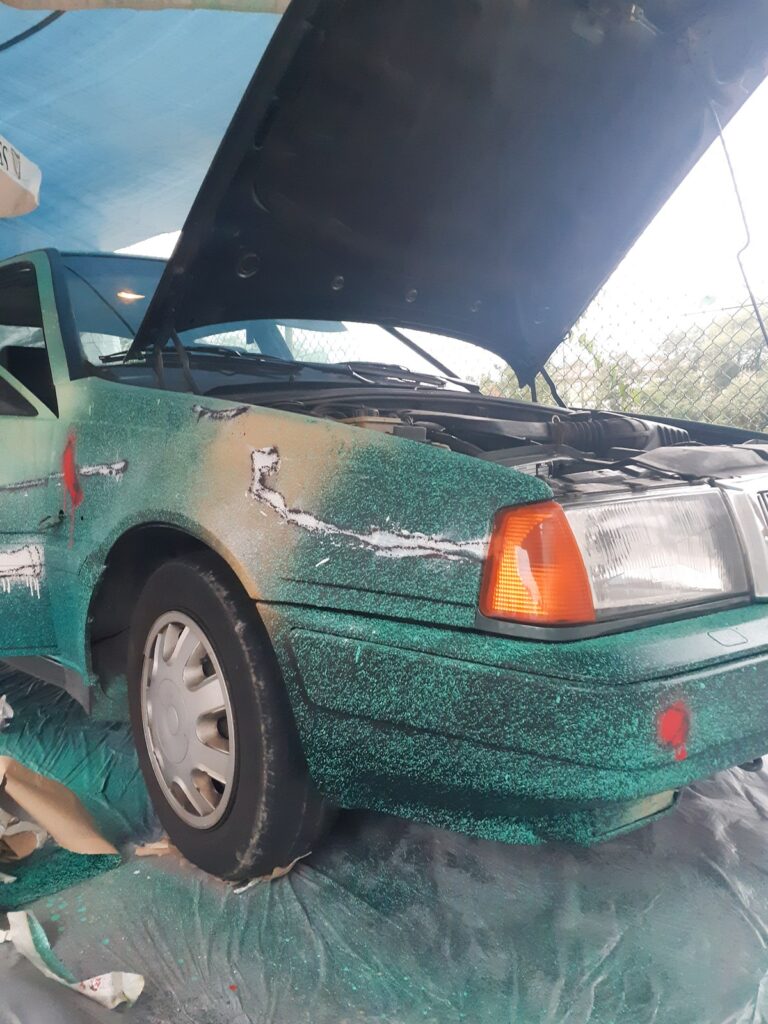 El coche con el capó abierto y trazos blancos sobre la aleta verde