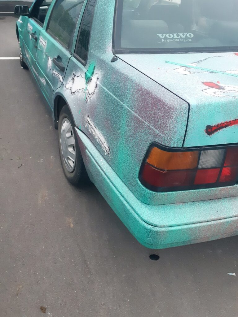 Lateral trasero del coche con trazos blancos, verdes y rojos sobre la chapa