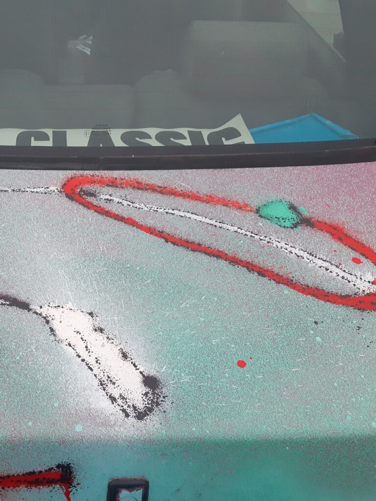 Detalle del maletero con trazos rojos, verdes y blancos sobre fondo verde claro