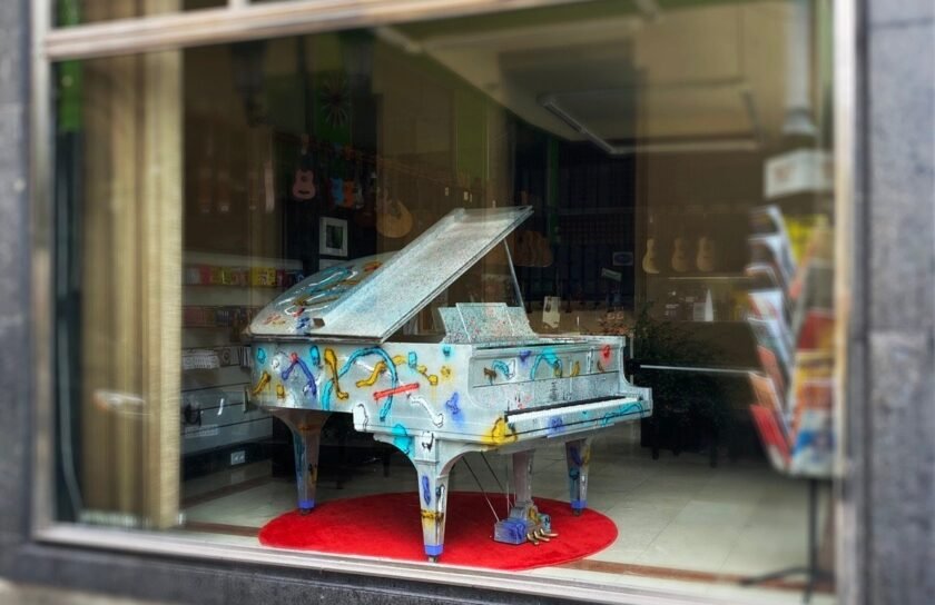 Piano de cola Hardman pintado por Sonek, visto desde la calle en el escaparate de Musical Arévalo, Oviedo