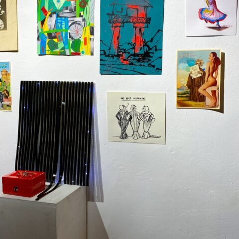 Una pieza turquesa de la serie Hórreos, con un hórreo negro y rojo, colgada entre obras de otros artistas