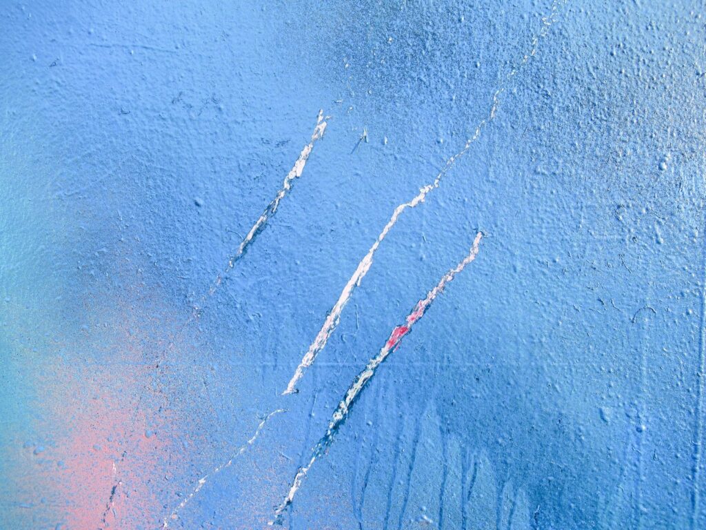 Detalle de un azul claro con tres trazos blancos rascados y una mancha rosa