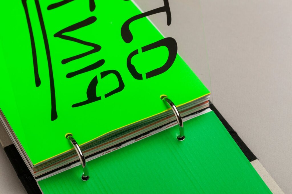 Separador verde flúor con letras negras pintadas, en las anillas del archivador de Ojo, Pinta!