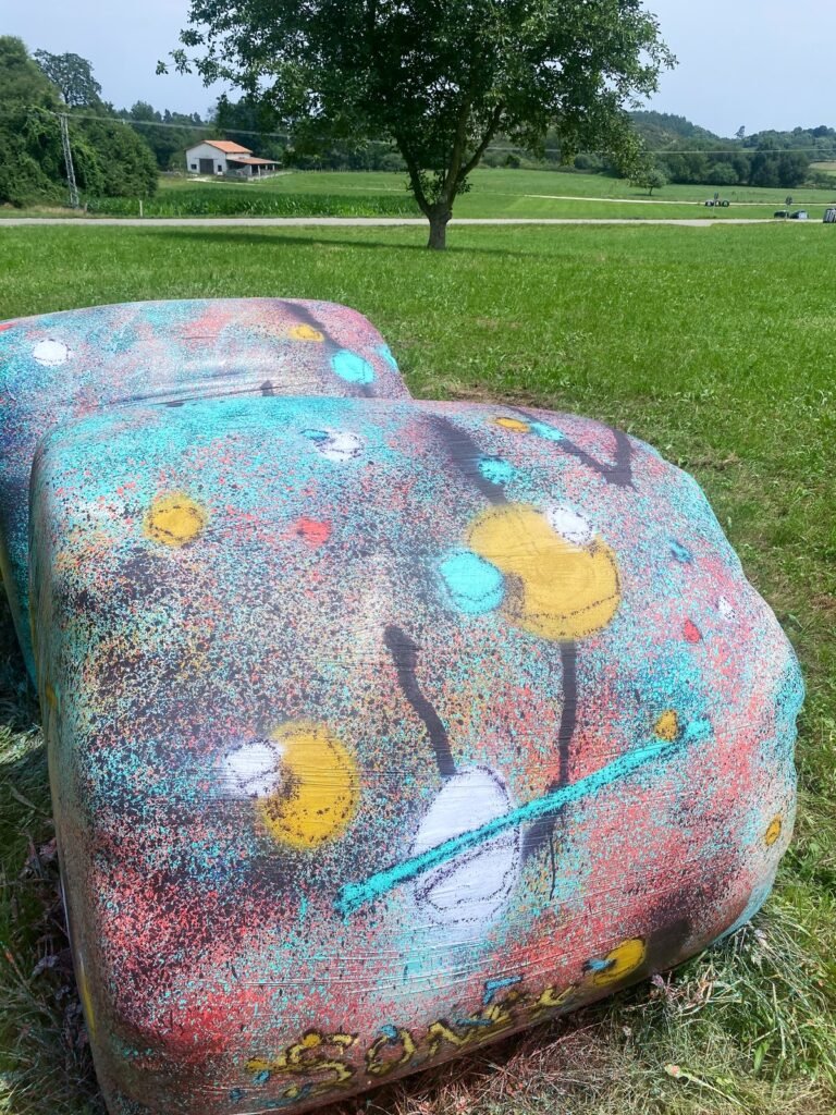 Una bola de silo vista de cerca a la luz del día, con amarillo y blanco, líneas turquesa y la firma SONEK en la base.