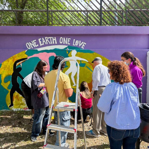 El grupo de jóvenes y mayores pinta junto el mural One Earth One Love en Soto del Real.