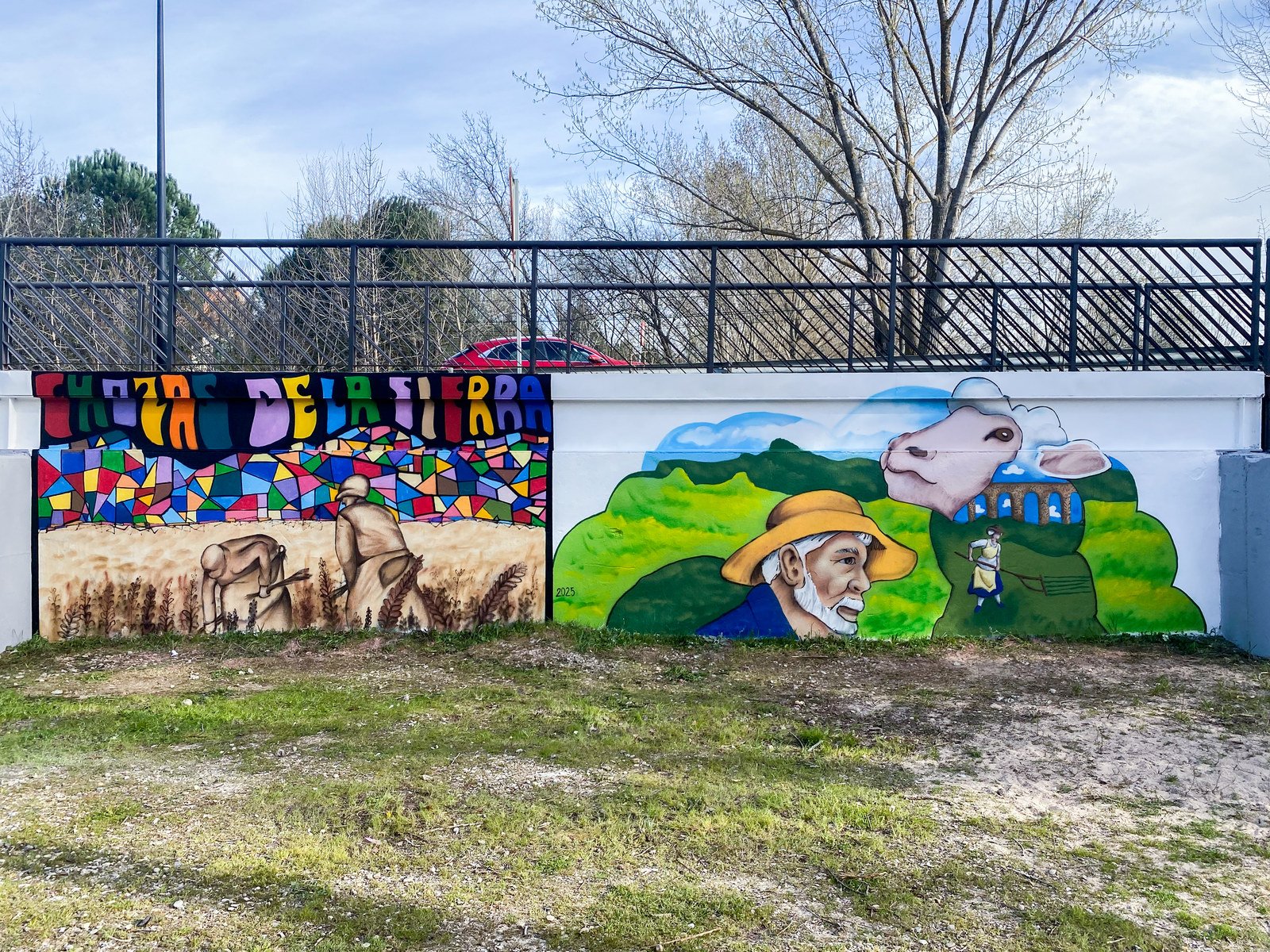 Mural terminado en Soto del Real, pintado en un taller intergeneracional: letras de colores, campos y un hombre con sombrero junto a una vaca.