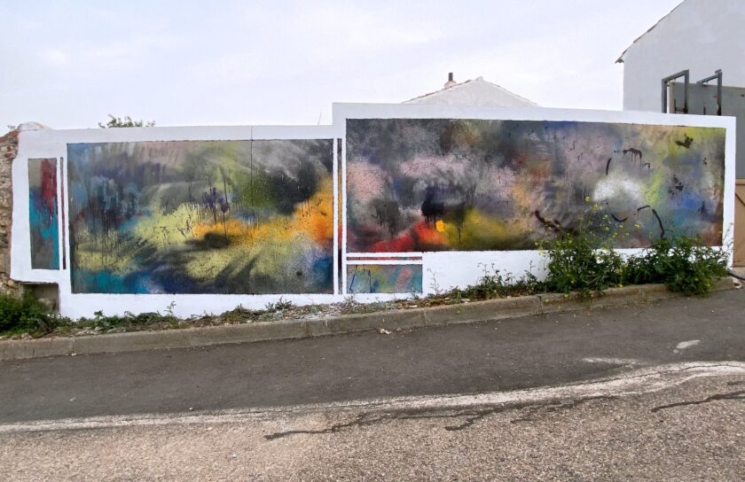 Mural abstracto de spray en azules, amarillos, rosas y rojos sobre un muro blanco de calle, visto de frente