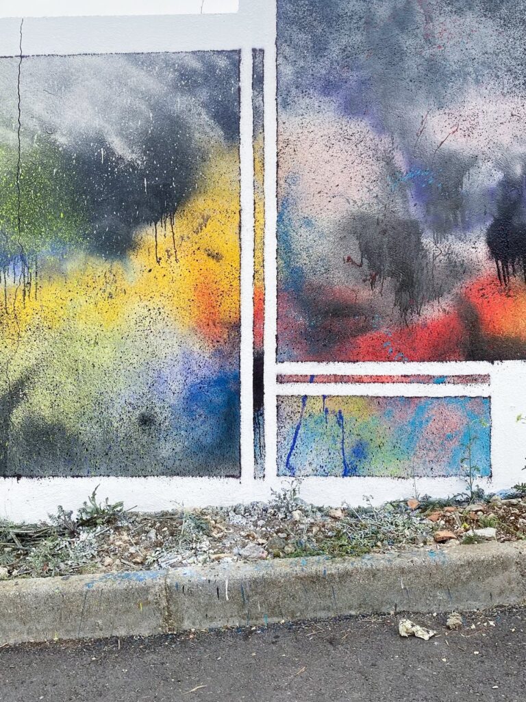 Tramo del mural enmarcado en blanco, con manchas oscuras, amarillas y rosas