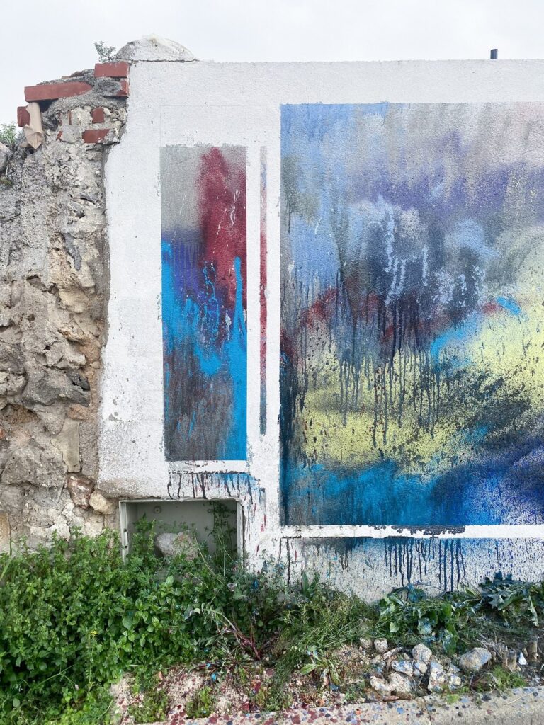 Tramo izquierdo del mural, junto a un muro de piedra, con manchas azules, rojas y amarillas
