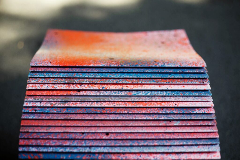 Pila de ejemplares del fanzine Pum con las portadas pintadas a spray en rojo y azul, sobre asfalto