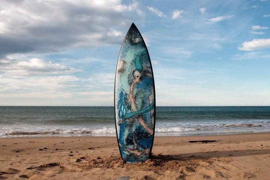 Marte 01, tabla de surf de SONEK, clavada en la arena frente al mar