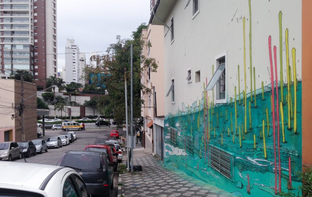 La fachada terminada en perspectiva desde la esquina, con los palos más altos sobre la pared blanca y la calle en pendiente.