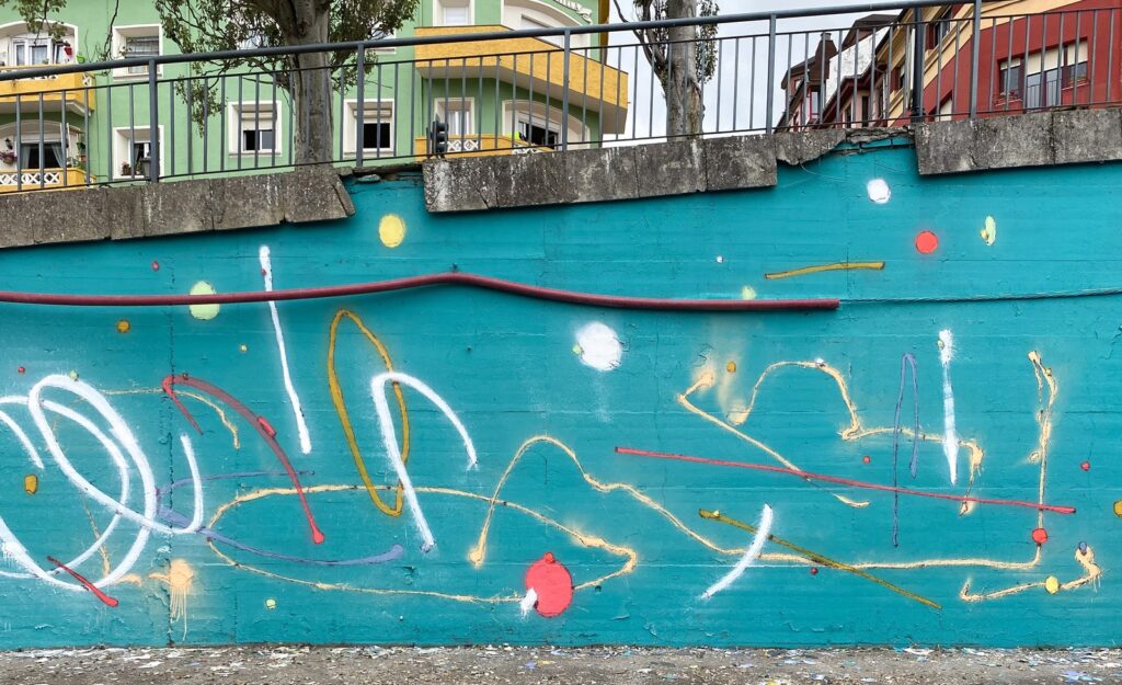 Primer plano del muro terminado, con trazos blancos, crema y rojos y la barandilla encima.