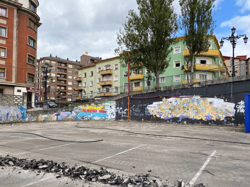 El solar con el muro de contención cubierto de grafitis, antes de pintar.