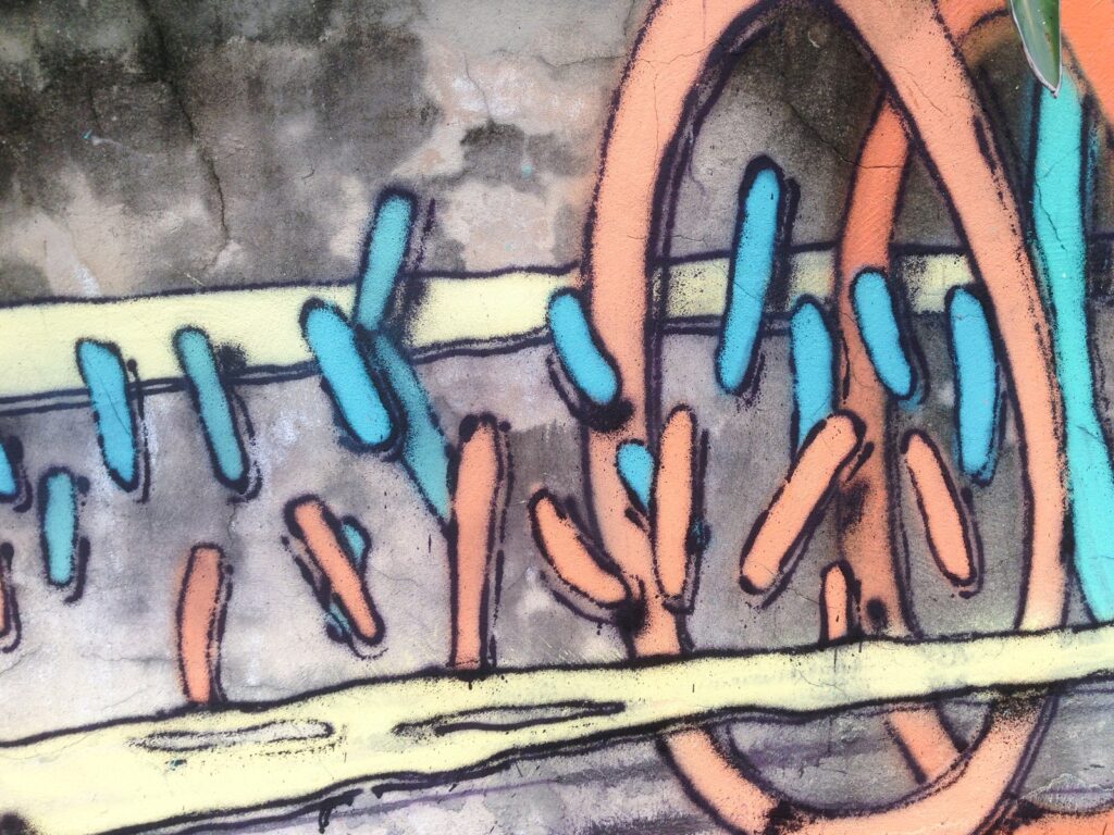 Detalle de dos aros naranjas y turquesas, con trazos azules y naranjas, sobre una barra amarilla.