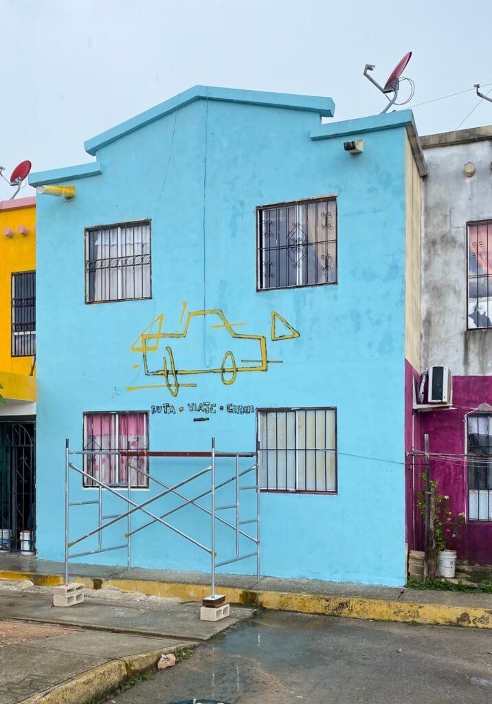La fachada ya azul, con las primeras líneas amarillas del coche y un andamio delante.