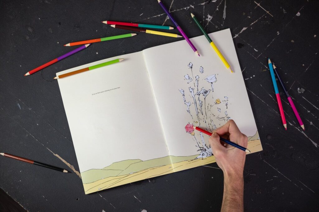 El cuadernillo abierto por la página «Si es un libro para colorear, no es para leer», con una mano coloreando unas flores